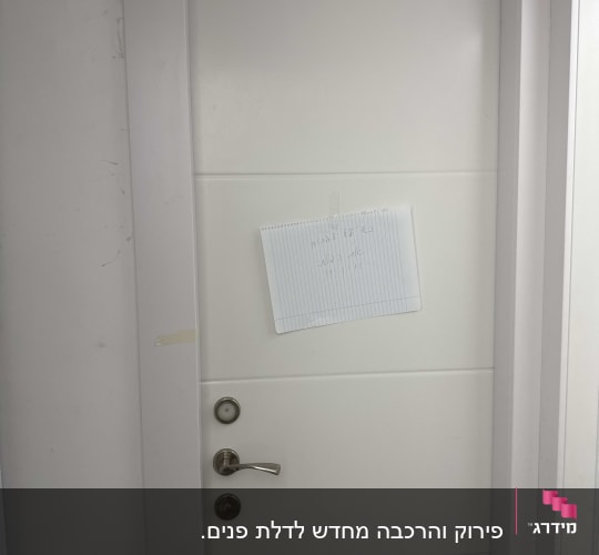 דלת לבנה עם ידית מתכת ודף נייר מודבק